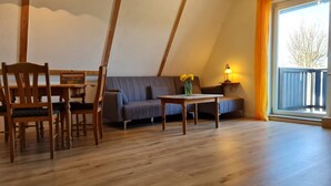 A cozy room with a wooden dining table, chairs, a sofa, and a small table with a lamp. - OR - Ferienhaus Mönchgutperle (Middelhagen)