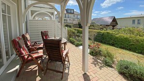 A covered patio with a table and chairs, a white fence, and a view of neighboring houses. - MR: Villa Wilhelmine Whg. 02 Wilhelm with terrace - Villa Wilhelmine Whg. 02 (Sellin)