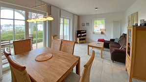 A spacious living room with a dining area, large windows, and a view of the outdoors. - MR: Villa Wilhelmine Whg. 02 Wilhelm with terrace - Villa Wilhelmine Whg. 02 (Sellin)