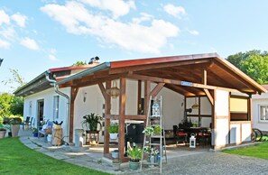 A covered outdoor seating area with wooden beams and potted plants.