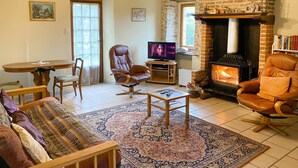 Ein gemütliches Wohnzimmer mit Kamin, Ledersesseln, Fernseher und Essbereich.