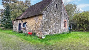 Ein Steinhaus mit geneigtem Dach, einer kleinen Veranda und einem Fenster.