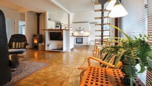Amplia sala de estar con chimenea, piso de madera y una planta grande.