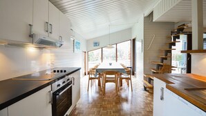 Una cocina moderna con un amplio comedor, suelo de madera y vistas a través de grandes ventanales.