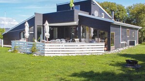 Una casa moderna con un patio cubierto, ventanas amplias y una terraza.