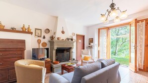 Ein Wohnzimmer mit Kamin, einer Couch, einem Fernseher und einem Sessel.