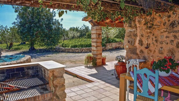 A patio with a grill, potted plants, and a view of a natural landscape. - Nice home in Pòrtol with kitchen (Pòrtol)