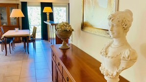 A dining area with a wooden table, chairs, a vase with flowers, and a bust sculpture on a wooden cabinet. - Residence Bleichröder App. Cosima, VS Sass (Heringsdorf)