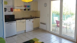 A compact kitchen with a microwave, dishwasher, and a sink. There is a dining area with a table and chairs visible through a glass door. - Stunning home in Torreilles - Plage (Torreilles - Plage)