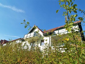 A two-story building with a red-tiled roof and a balcony.