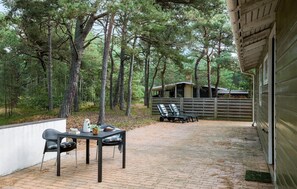 An outdoor patio with two chairs and a table, a wooden fence, and a building in the background. - Gorgeous home in Nexø with WiFi (Nexø)