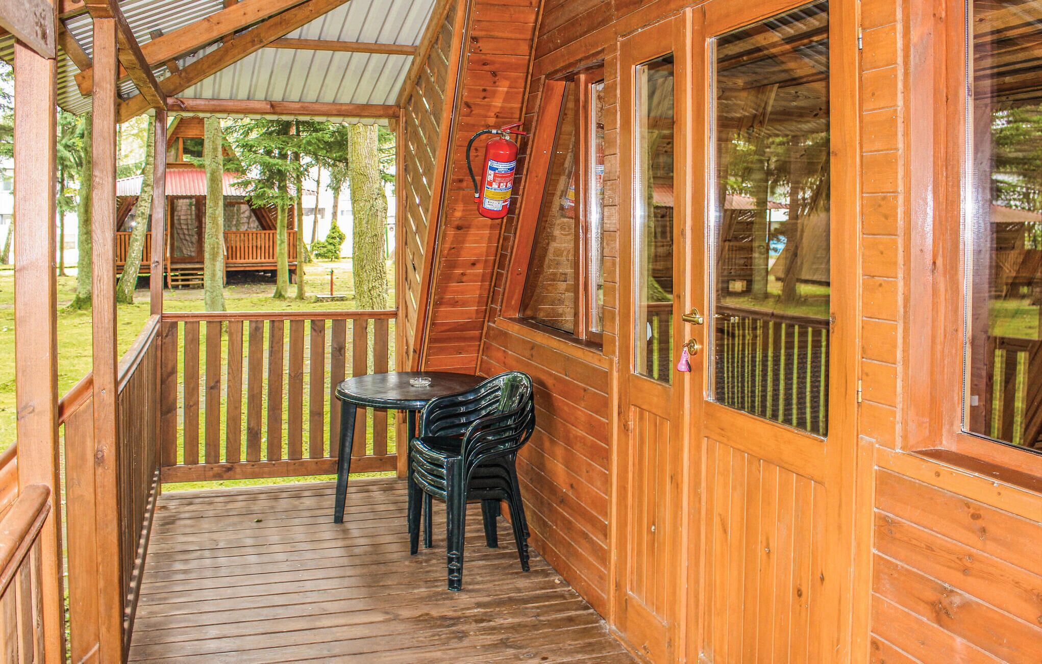Eine Holzblockhütte mit überdachter Veranda, einem Feuerlöscher und einem Tisch mit Stühlen.