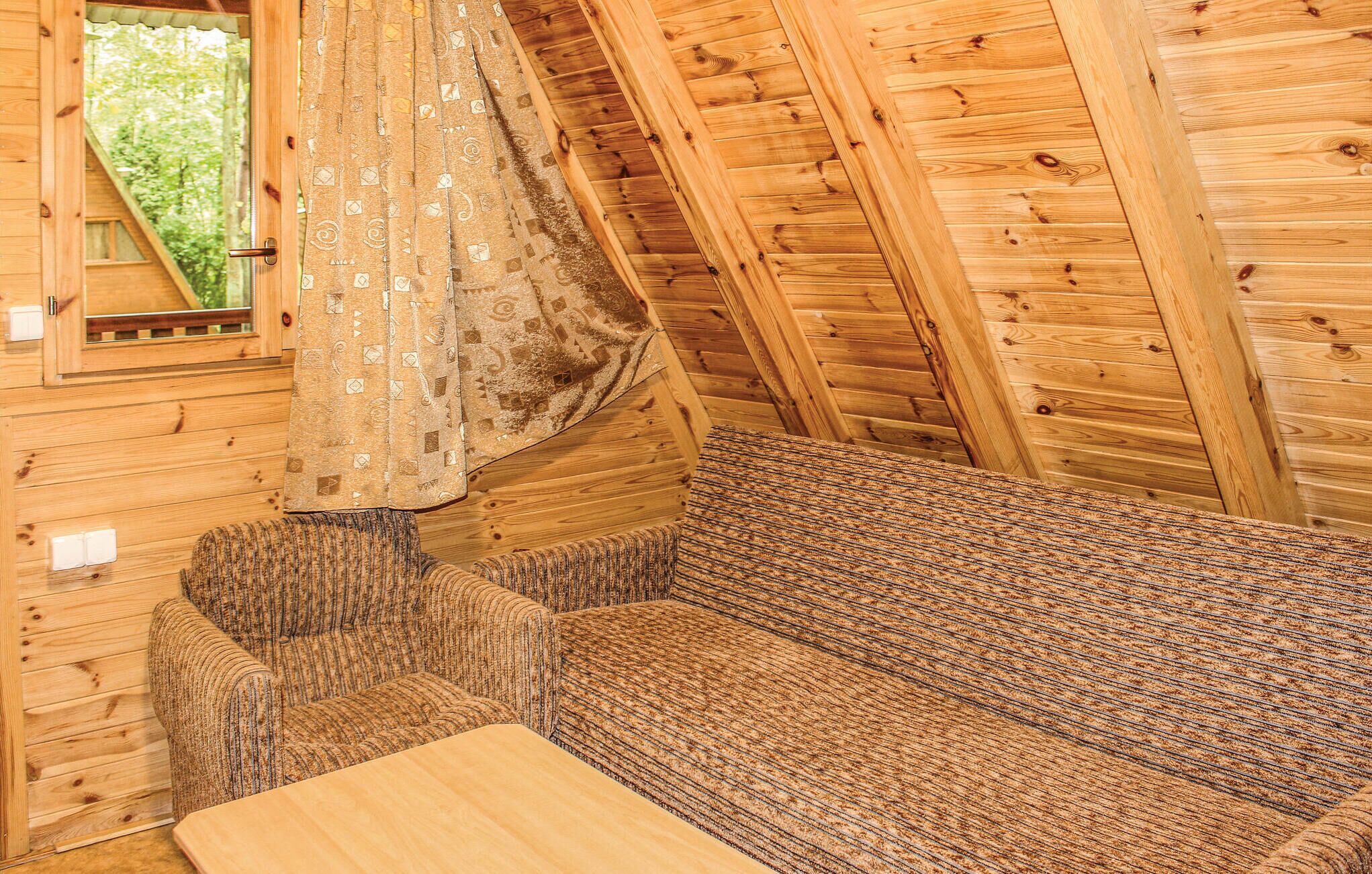 A cozy cabin interior with a wooden ceiling, a patterned sofa, and a small table.