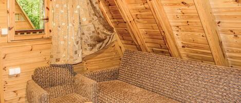 A cozy cabin interior with a wooden ceiling, a patterned sofa, and a small table.