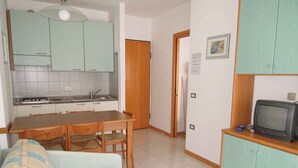 Un espai vital reduït amb una cuineta, zona de dinar, sofà i televisió.