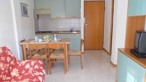 Un espai vital compacte amb zona de menjador, petita cuina i televisió.