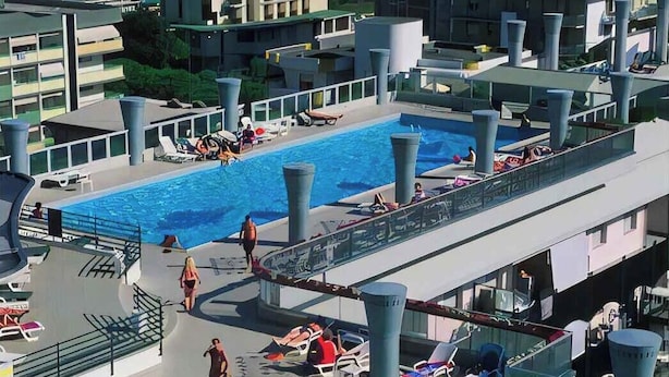 Zona de piscina al terrat amb diverses piscines, gandules i vista a l'oceà.