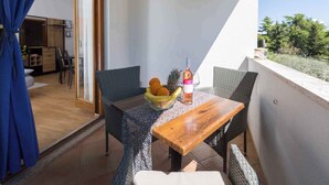 Uma varanda com mobiliário de vime, uma mesa de madeira e uma cesta de frutas.