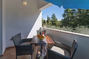 A balcony with wicker furniture, a wooden table, and a bowl of fruit.