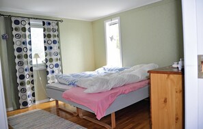 A bedroom with a bed, a wooden dresser, a window with curtains, and a rug on the floor. - Lovely home in Hedekas with ethernet internet (Hedekas)