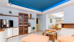 A modern living room with a flat-screen TV, wooden cabinets, a dining area, and a kitchen in the background. - Awesome apartment in Slano with sauna (Slano)