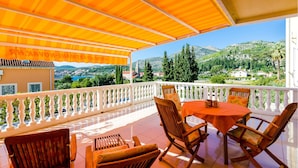 A terrace with a view of a coastal town, furnished with wooden chairs and a table, and a white balustrade. - Awesome apartment in Slano with sauna (Slano)