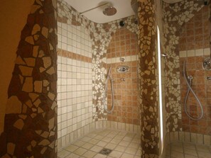 A shower with mosaic tile walls and a drain in the center. - 104 - Pension Stallinger (Weyregg am Attersee)