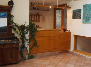 A reception area with a wooden counter, a potted plant, and a fireplace. - 104 - Pension Stallinger (Weyregg am Attersee)
