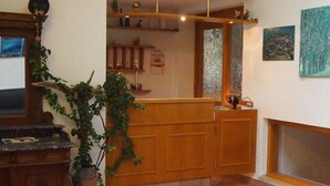 Una zona de recepción con mostrador de madera, una planta en maceta y una chimenea.