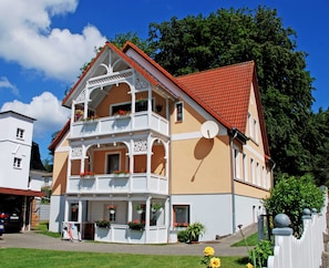 Un bâtiment à deux étages doté d’un balcon, d’un toit rouge et d’une façade blanche.