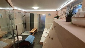 Een moderne badkamer met een douchecabine van glas, een zitbankje en een wastafelgedeelte met toiletartikelen.
