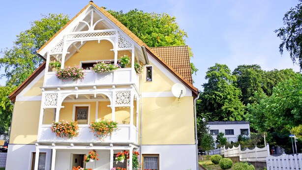Een huis met twee verdiepingen, een balkon, een schotelantenne en bloembakken.