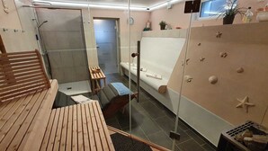 Hotelkamer met een houten bankje, een bed met een witte hoofdbord, een tafeltje en een wand versierd met zeesterren.