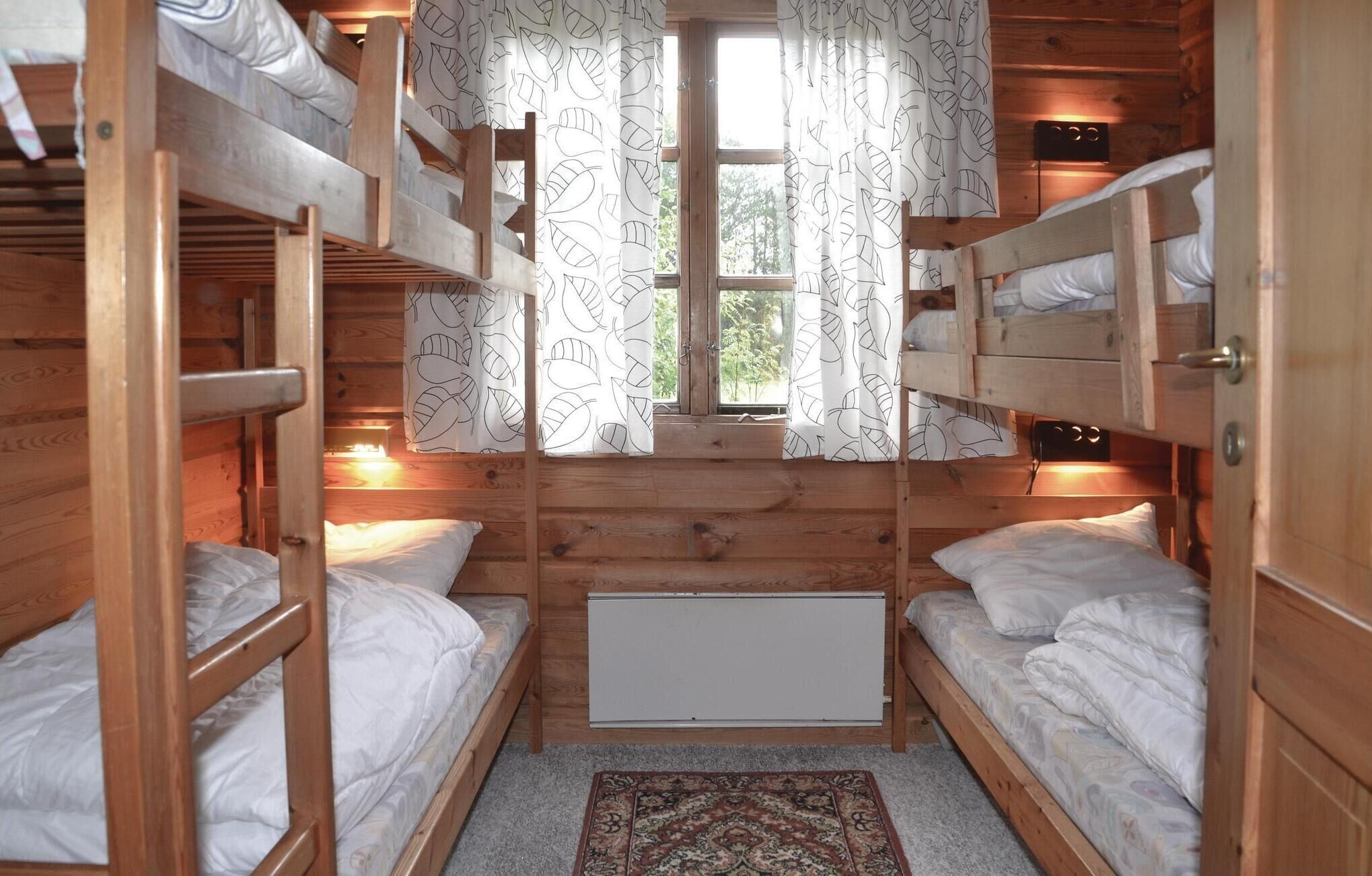 A cabin with bunk beds, a window with curtains, and a radiator.