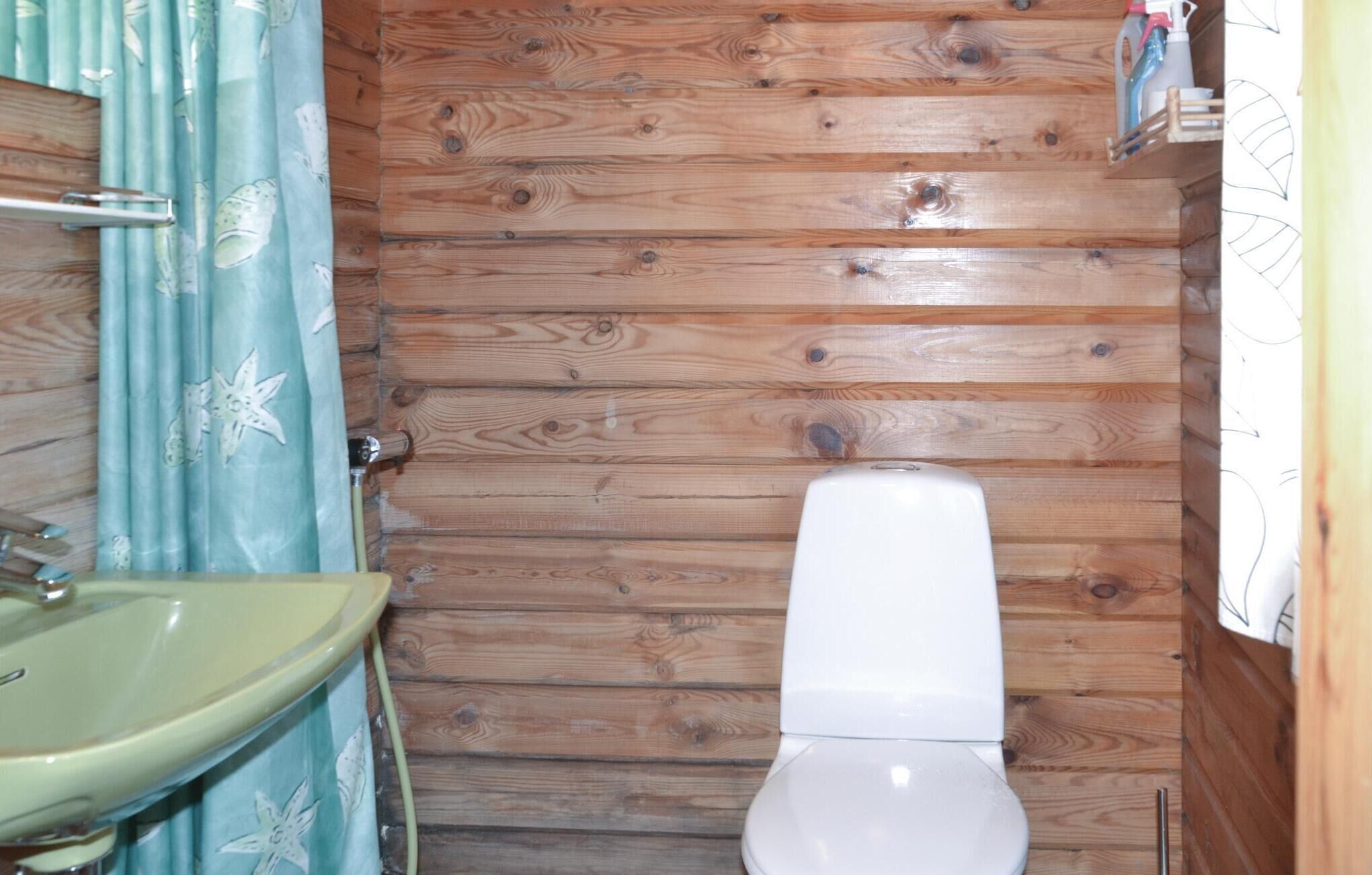 Een badkamer met een houten wand, een wit toilet en een wastafel met een groene wasbak.
