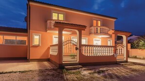 Una casa de dos pisos con balcón y entrada protegida por una reja.