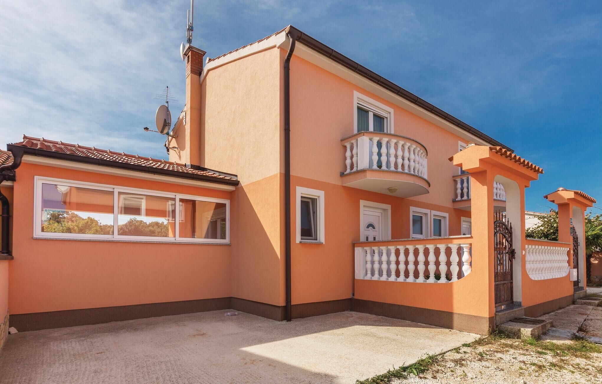 A two-story building with a balcony, a satellite dish, and a gated entrance.