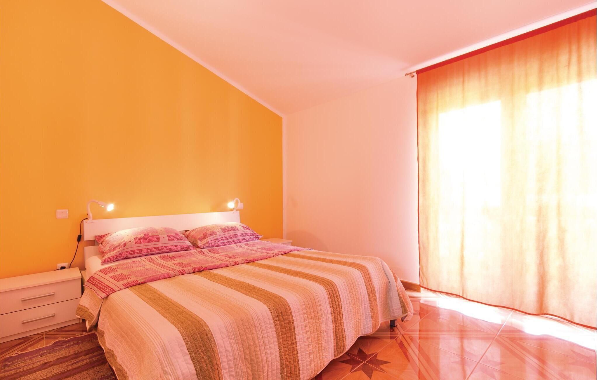 A bedroom with a bed, a nightstand, a lamp, and a window with curtains.