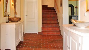 A hallway with a brick floor, white walls, a white door, and a staircase leading to another room. - Holiday Sundevit 1st - Holiday Sundevit (Prerow)