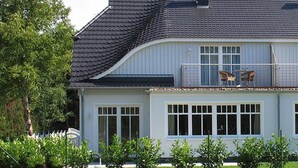 A two-story house with a dark roof, large windows, and a balcony with chairs. - Holiday Sundevit 1st - Holiday Sundevit (Prerow)