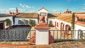 Une cour avec un bâtiment blanc portant l’inscription « Santa Maria », doté d’un toit en tuiles et de fenêtres en arc de cercle.