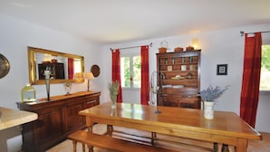 Zona pranzo con tavolo e panche in legno, uno specchio, una lampada e una mensola con oggetti decorativi.