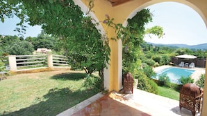 Un patio con piscina, circondato da vegetazione e un recinto in legno.