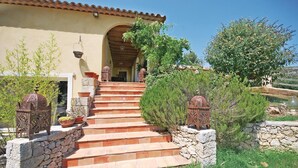 Una casa con una scala in pietra che conduce a una porta in legno, circondata dal verde e lanterne decorative.