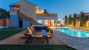 Ein modernes, zweistöckiges Haus mit Whirlpool, Holzterrasse und Schwimmbad.