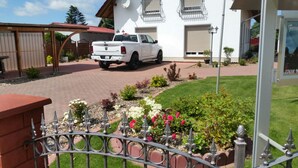 Een witte pick-up truck geparkeerd voor een huis met een pad van bakstenen dat naar de ingang leidt.
