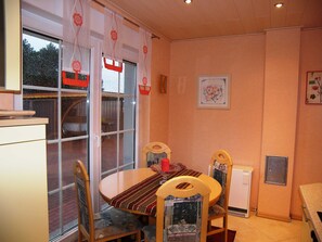 Un coin repas avec une table ronde, des chaises et une fenêtre avec des rideaux.