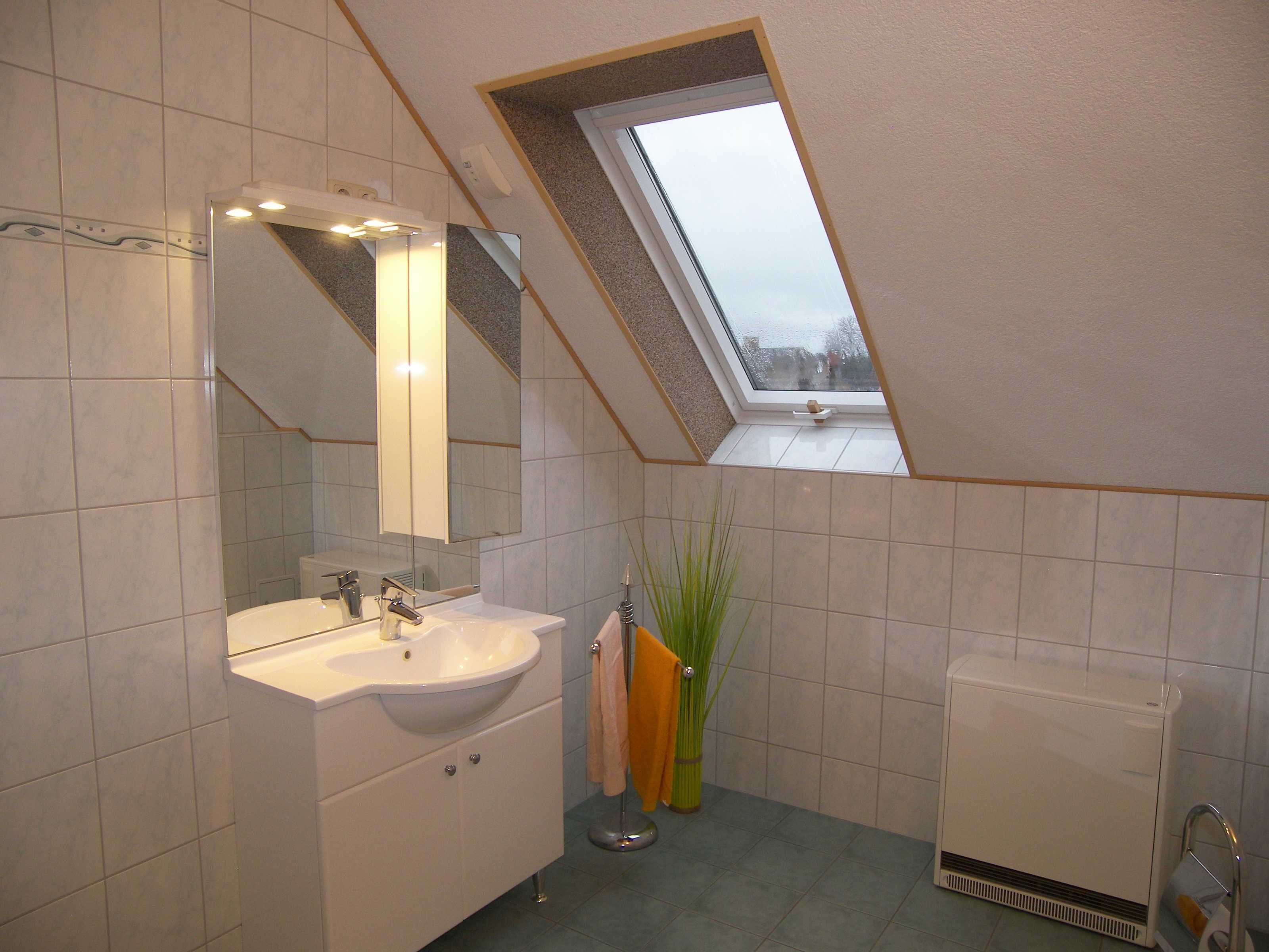 A bathroom with a skylight, a sink, a mirror, a towel rack, and a radiator.