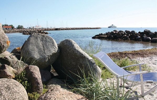 A rocky shoreline with a chair and a rocky breakwater in the background. - Cozy home in Rudkøbing with WiFi (Rudkøbing)