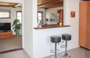 A modern kitchen with a wooden countertop, two black bar stools, and a brick backsplash. - Cozy home in Rudkøbing with WiFi (Rudkøbing)